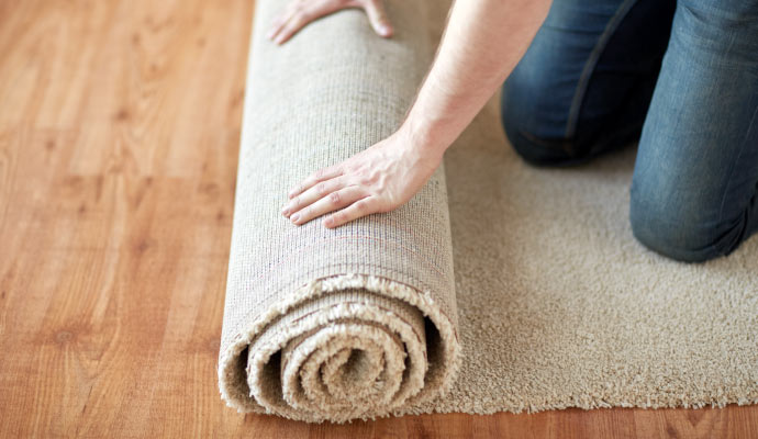 a person rolling up a carpet on a wooden floor