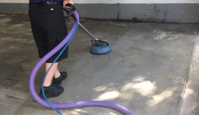 professional worker cleaning concrete floor with industrial cleaning equipment