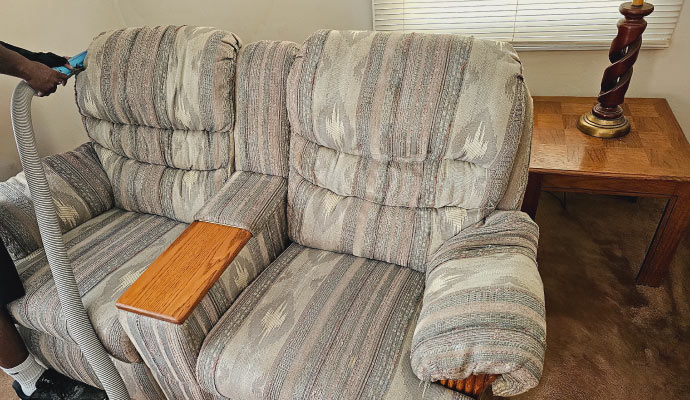 a person vacuuming a sofa in the living room